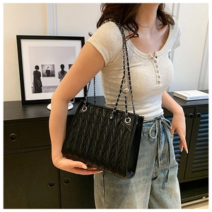 Detail of black pleated PU leather shoulder bag with silver chain strap and metal eyelets