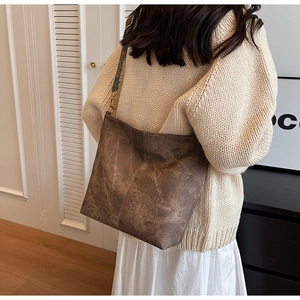 Close-up of brown vintage tote bag with ethnic patterned wide strap on a model