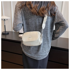 Détail du sac bandoulière blanc cassé avec cuir texturé et sangle à motifs géométriques