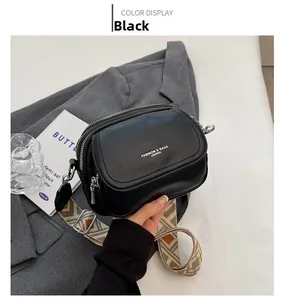 Gros plan sur le sac carré noir avec texture litchi et large bandoulière géométrique