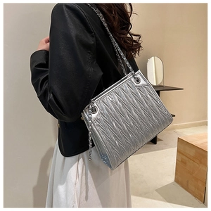 Detail of silver pleated texture shoulder bag with metallic chain strap on model