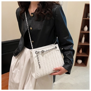 Detailed view of white quilted褶皱 handbag featuring silver chain accents and wave texture