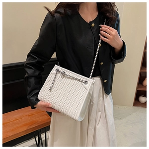 Macro view of white pleated matelassé texture on a crossbody bag with silver chain strap