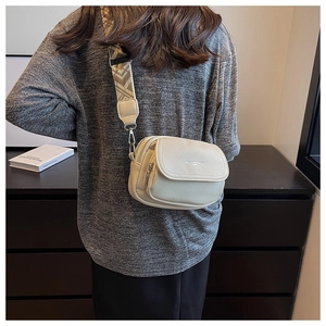 Détail du sac à bandoulière crème avec double fermeture éclair et large sangle géométrique