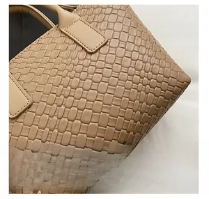 Macro detail of tan woven leather texture and reinforced stitching on tote bag handle