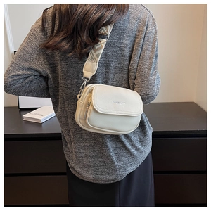 Détail du sac bandoulière blanc cassé avec texture litchi et sangle en jacquard