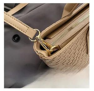 Close-up of golden hardware and woven leather texture on a beige tote bag