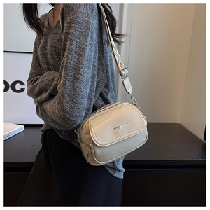 Détail du sac bandoulière beige avec grain de litchi et sangle tissée ethnique