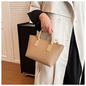 Detail of beige woven tote bag with intricate cross-stitch texture and leather straps
