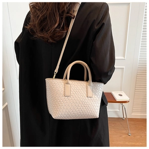 Close-up of cream woven leather tote bag showing intricate cross-weave texture and strap