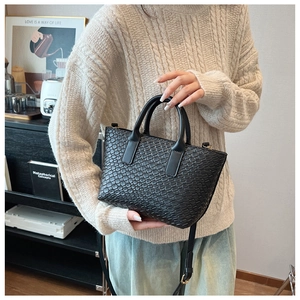 Detailed view of black woven texture tote bag with double handles and adjustable strap