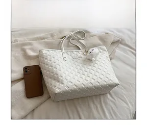Sac fourre-tout matelassé blanc comparé à un smartphone avec un charm pompon doux