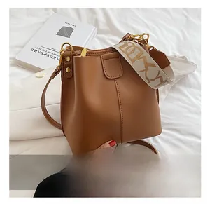 Détail d'un sac seau en cuir caramel avec deux bandoulières et coutures verticales