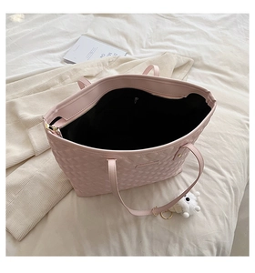Gros plan du sac cabas matelassé rose avec pompon blanc et détails de fermeture éclair