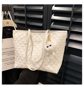 Gros plan sur un sac cabas blanc matelassé avec un charmant pompon à gros yeux