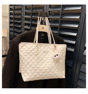 Détail du sac cabas matelassé blanc avec clous dorés et breloque en peluche sur veste