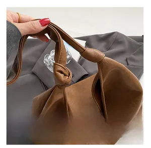 Detail of knotted leather strap and fine stitching on a vintage brown soft bucket bag