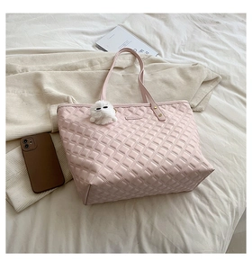 Détail du sac cabas rose matelassé avec logo en métal et pendentif en peluche blanche