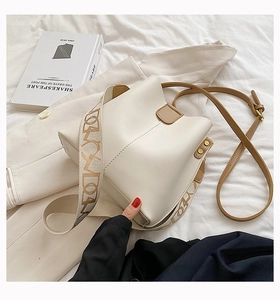 Détail du sac seau crème avec bandoulière large en tissu et sangle en cuir
