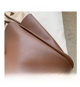 Detailed close-up of dark brown tote bag showing pebbled leather texture and metal studs