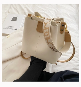 Détail du sac seau crème avec garniture en cuir marron et bandoulière en tissu stylée