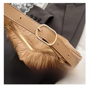 Detail of adjustable gold oval buckle and pleated leather texture on caramel bag