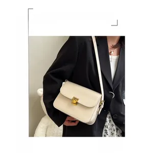 Détail d'un sac bandoulière en cuir crème avec une boucle métallique dorée rétro élégante