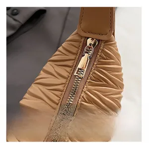 Macro detail of camel pleated handbag featuring smooth golden metal zipper closure