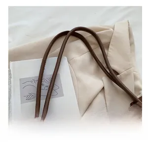 Detail of the slim brown leather shoulder strap with fine stitching on a tote bag