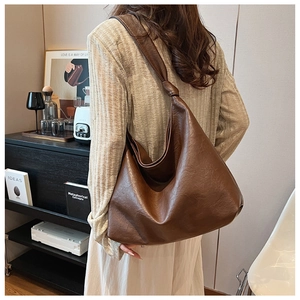 Detail of a dark brown hobo bag featuring a unique handcrafted knotted shoulder strap