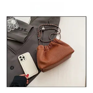 Brown pleated bucket bag size comparison with smartphone on grey blazer fabric