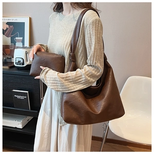 Deep brown vintage soft leather tote bag with a matching small clutch on a table