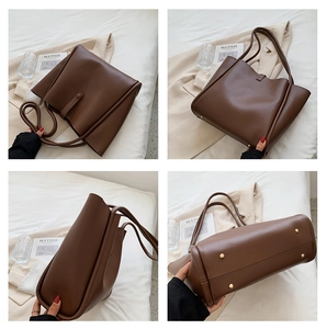 Detail view of large brown leather tote bag showing textured finish and protective metal feet