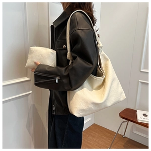Detail of cream pleated tote bag featuring a matching zipper pouch and decorative knots