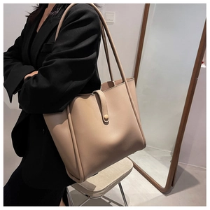 Detailed view of the large apricot tote bag on a model wearing a black blazer