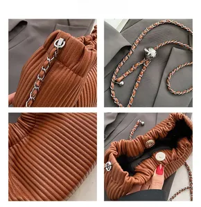 Detail of brown pleated cloud bag featuring metal chain strap and magnetic closure