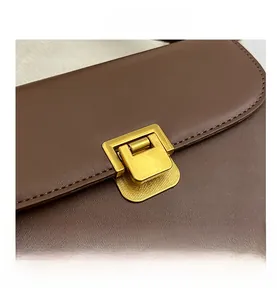Détail macro du sac en cuir marron avec boucle dorée rectangulaire et couture précise