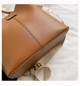 Détail du sac seau en cuir marron avec coutures verticales et bandoulière tressée