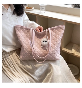 Détail du sac cabas rose matelassé avec étiquette en cuir et peluche monstre
