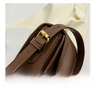 Détail de la boucle réglable en métal doré sur la bandoulière en cuir marron foncé