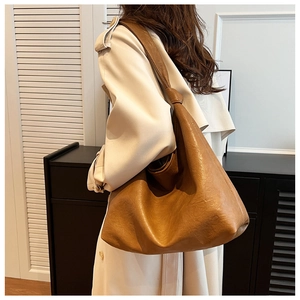 Brown leather hobo bag with knotted strap detail shown on model in a minimalist setting