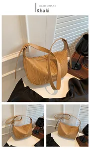 Detail of khaki pleated crescent bag with gold metal logo and adjustable leather strap