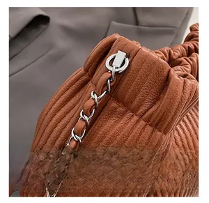Detail of silver metal hardware and chain strap on brown leather pleated bucket bag