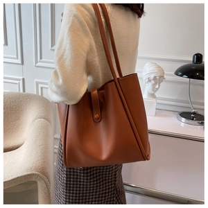 Brown faux leather tote bag with fine texture shown on a model in a minimalist interior