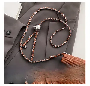 Detail of a brown pleated leather bucket bag with silver chain strap and metal ball buckle