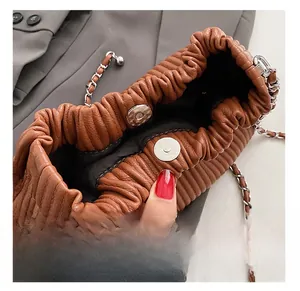 Detail of the magnetic buckle and pleated leather texture on a brown bucket bag