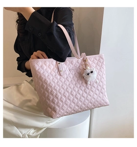Détail du sac cabas rose matelassé avec lettrage en métal et pendentif en peluche blanc