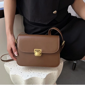 Détail d'un sac à bandoulière vintage en cuir marron avec un fermoir en métal doré