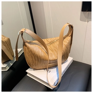 Detail of khaki pleated dumpling bag with golden zipper and adjustable wide strap