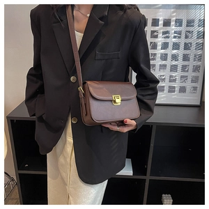 Détail du sac vintage en similicuir marron foncé avec boucle dorée et bandoulière